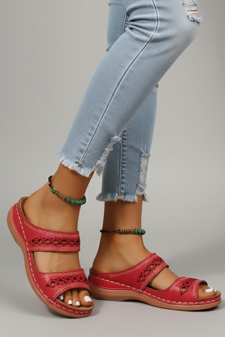 Side profile of a woman's foot in a beige dual strap slide sandal with decorative cutouts, summer style.