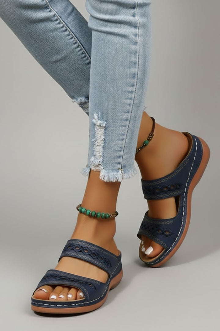 Woman wearing black dual strap slide sandals with decorative cutouts, perfect for vacation or casual wear.