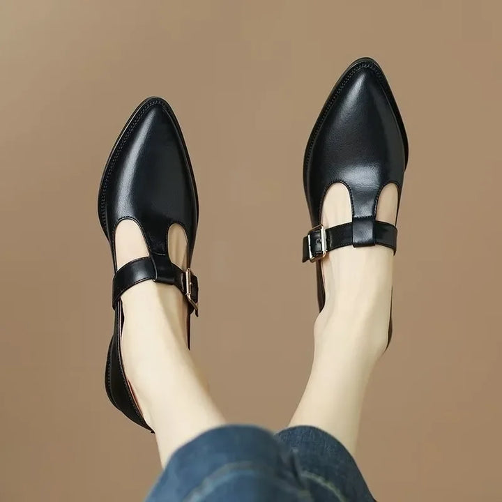 Close-up of women's black pointed toe T-strap block heels, showcasing block heel and strap detail.