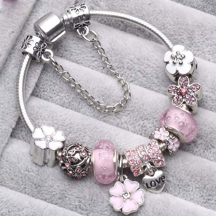 Close-up of a women's peach blossom charm bracelet. Dainty, elegant wrist accessory with a beautiful blossom motif.