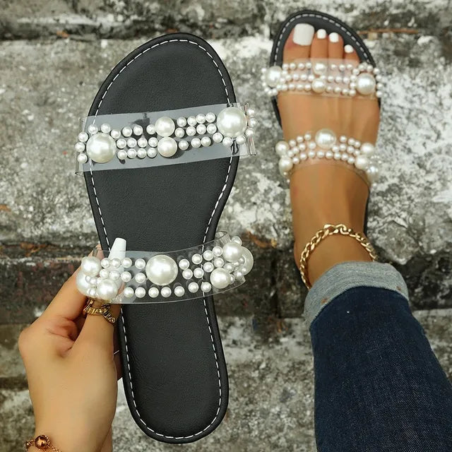 Stylish women's comfortable pearl flat slides, featuring transparent straps & slip-on design for summer.