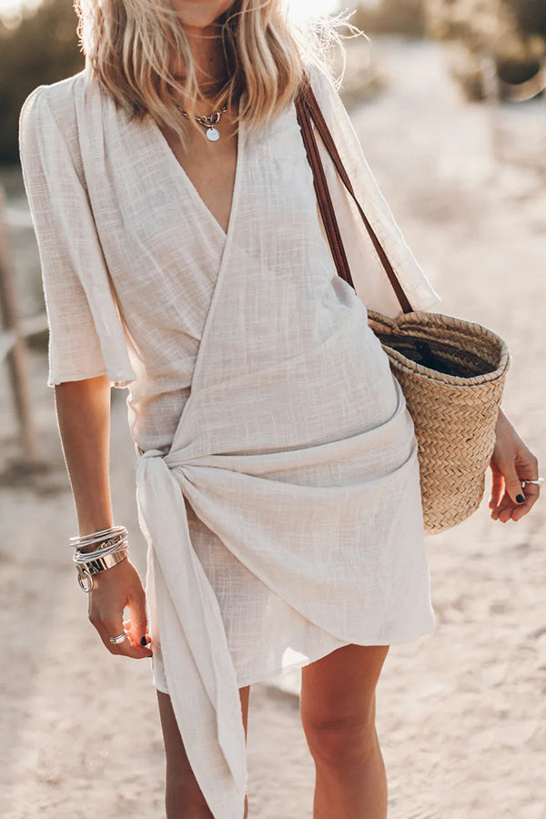 Women's elegant wrap mini dress with asymmetrical hem in a lightweight summer fabric, front view.