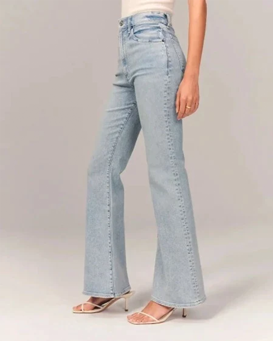 Close-up of women's light blue flared high-waisted denim jeans texture, showing stitching detail
