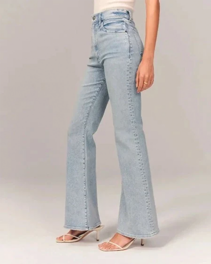 Close-up of women's light blue flared high-waisted denim jeans texture, showing stitching detail