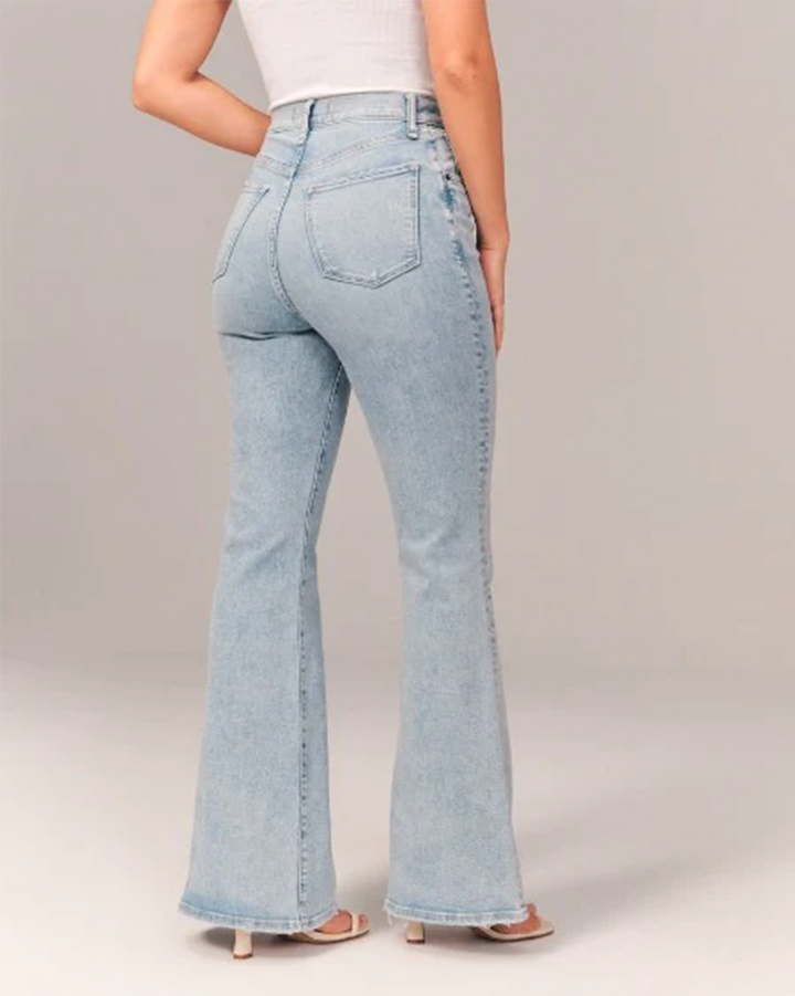 Model wearing women's dark blue flared high-waisted denim jeans, showcasing fit & style