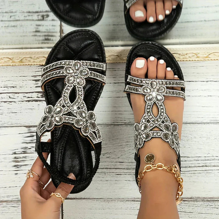 Close-up of a women's flat sandal with intricate floral embellishments on the straps