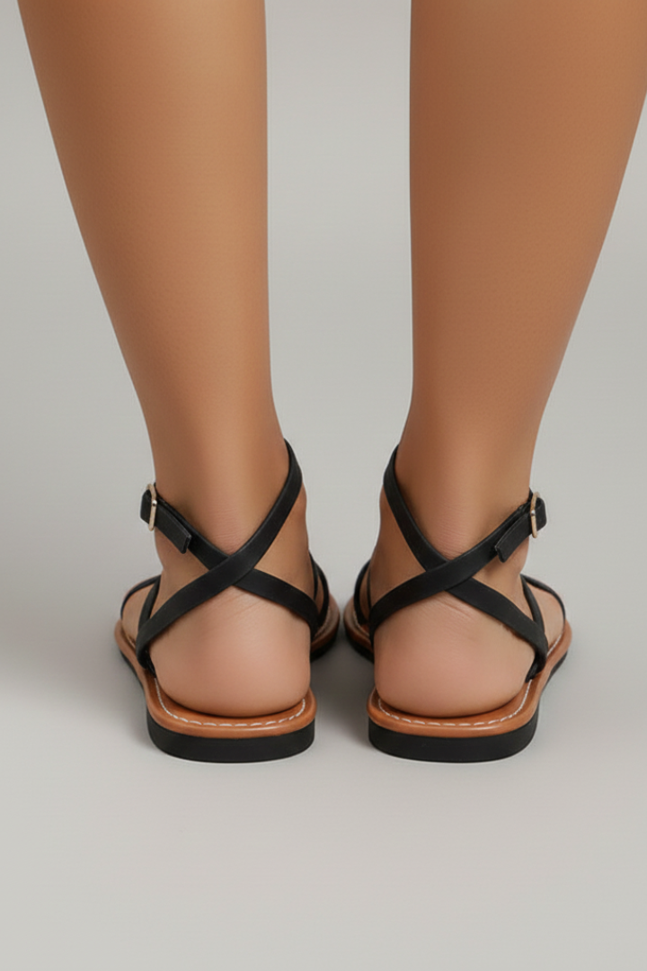 Close-up of elegant women's flat sandals featuring delicate strappy design and secure ankle strap.