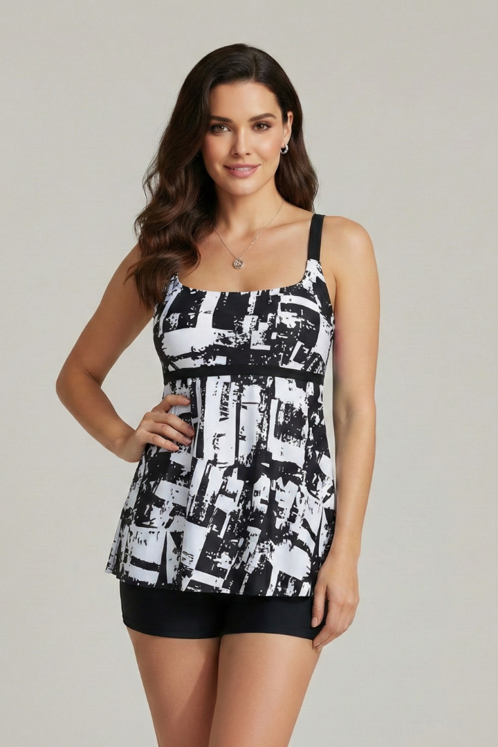 Women's vacation outfit: patterned tankini top and black swim shorts, offering modest swimwear style.