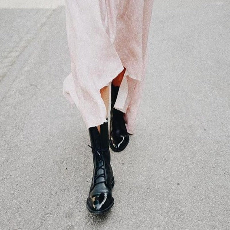 Close-up of a women's formal black ankle boot, showcasing intricate lace-up detail and polished finish.