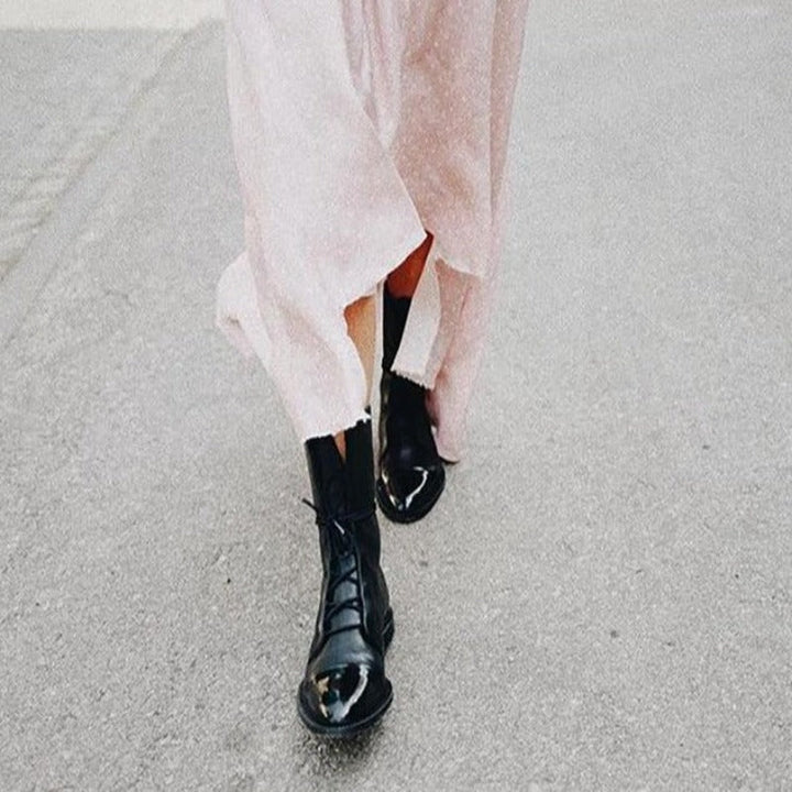 Close-up of a women's formal black ankle boot, showcasing intricate lace-up detail and polished finish.