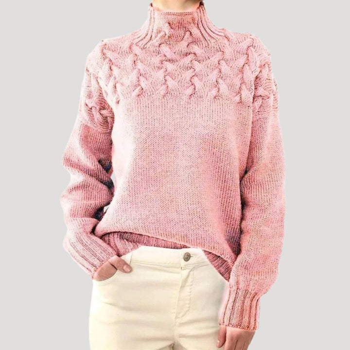Close-up of a women's cream cable knit sweater, highlighting the intricate knitwear pattern and high neck.