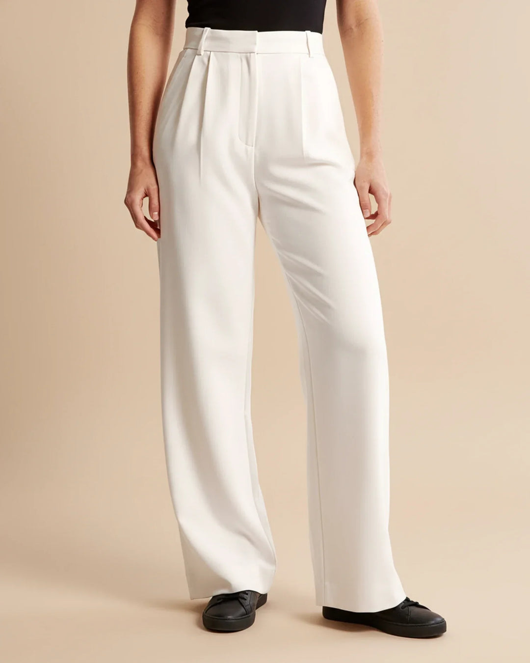 Stylish women's high waist pleated tailored trousers paired with a blouse, great for business meetings.
