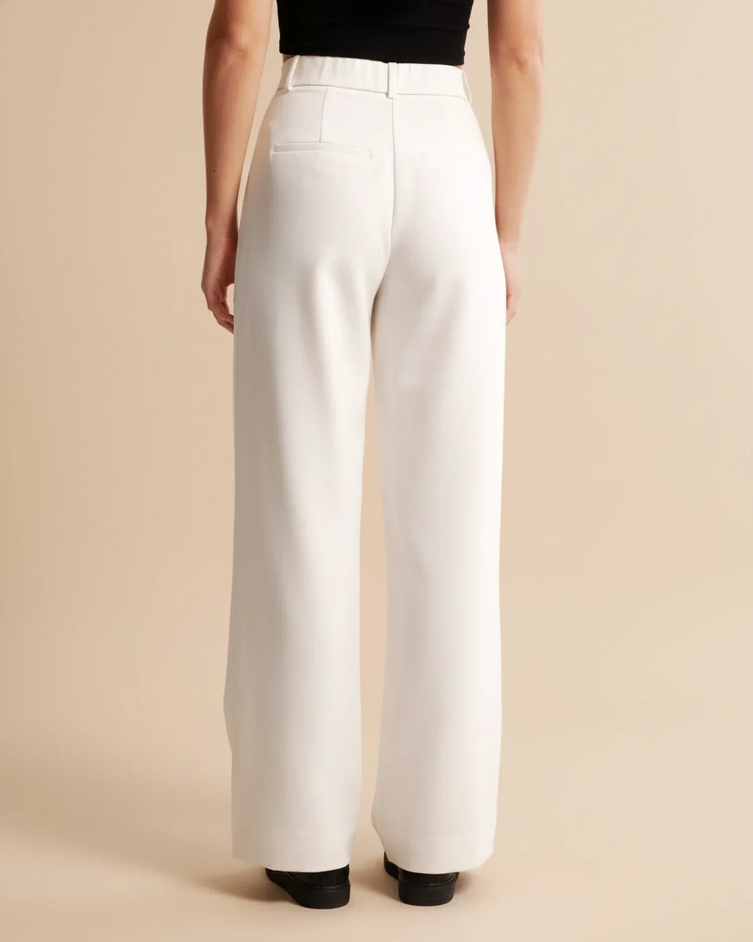 Back view of women's tailored high waist pleated trousers, showcasing a flattering silhouette.