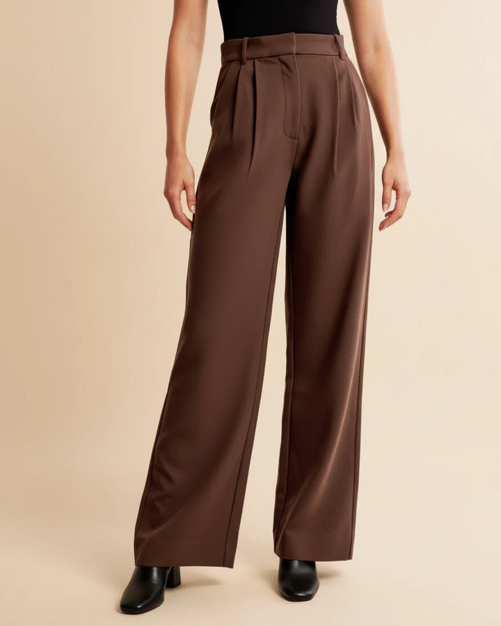 Studio shot of women's high-waisted pleated tailored trousers, highlighting their structure and fabric.