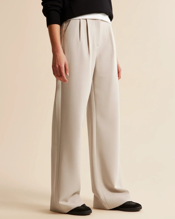 Close-up of the pleats on women's high-waisted tailored trousers, highlighting the detailed design.