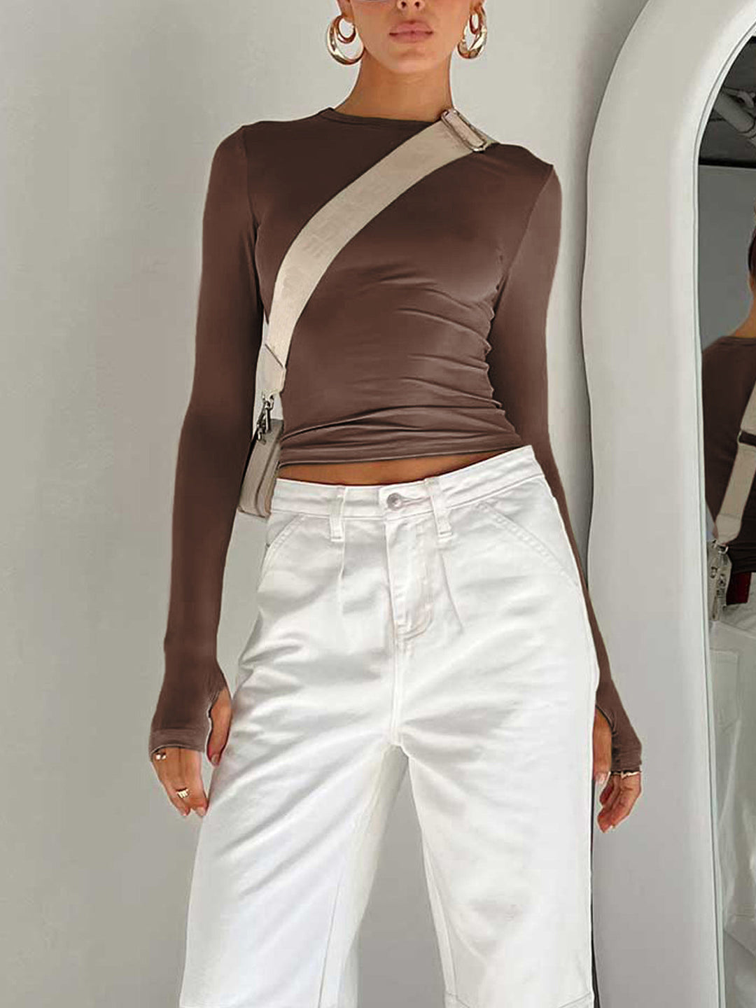 Side profile of a woman wearing a chic long sleeve crop top, suitable for summer fashion