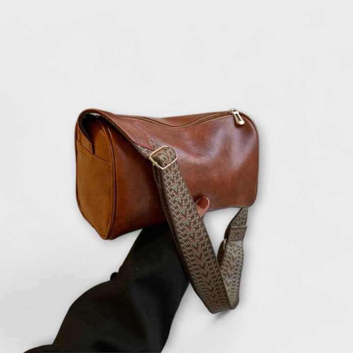 Modern women's shoulder bag with an eye-catching patterned strap, held by a model.