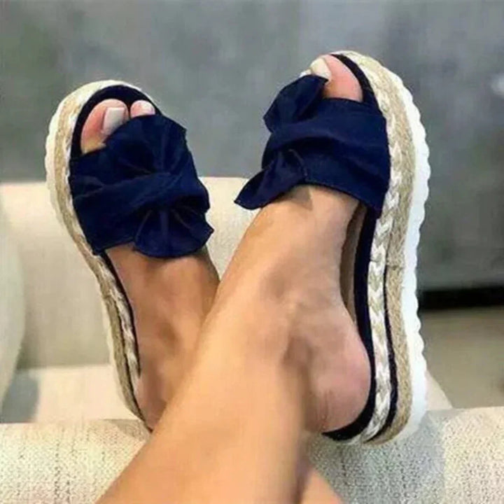 Close-up of white bow detail on women's platform slide sandal, highlighting spring style