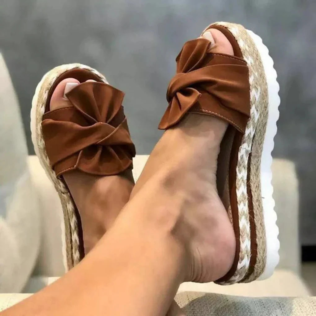 Top view of a woman's foot wearing a fashionable red bow platform slide sandal for comfort