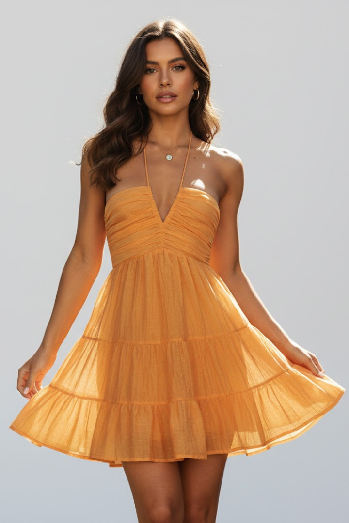 Back view of a women's pink halter neck mini dress, highlighting the ties and flowy tiered skirt design.