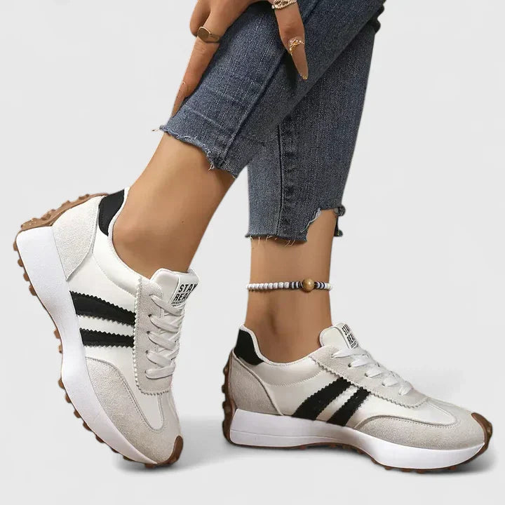 Pair of women's retro white sneakers with classic lace-up design, ideal comfortable footwear for daily use.