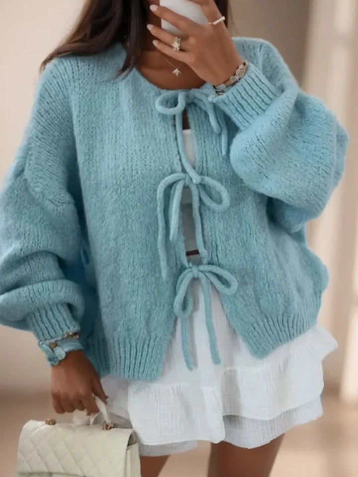 Soft knit women's cardigan in a vibrant color, detailed with elegant bow ties for a feminine look.