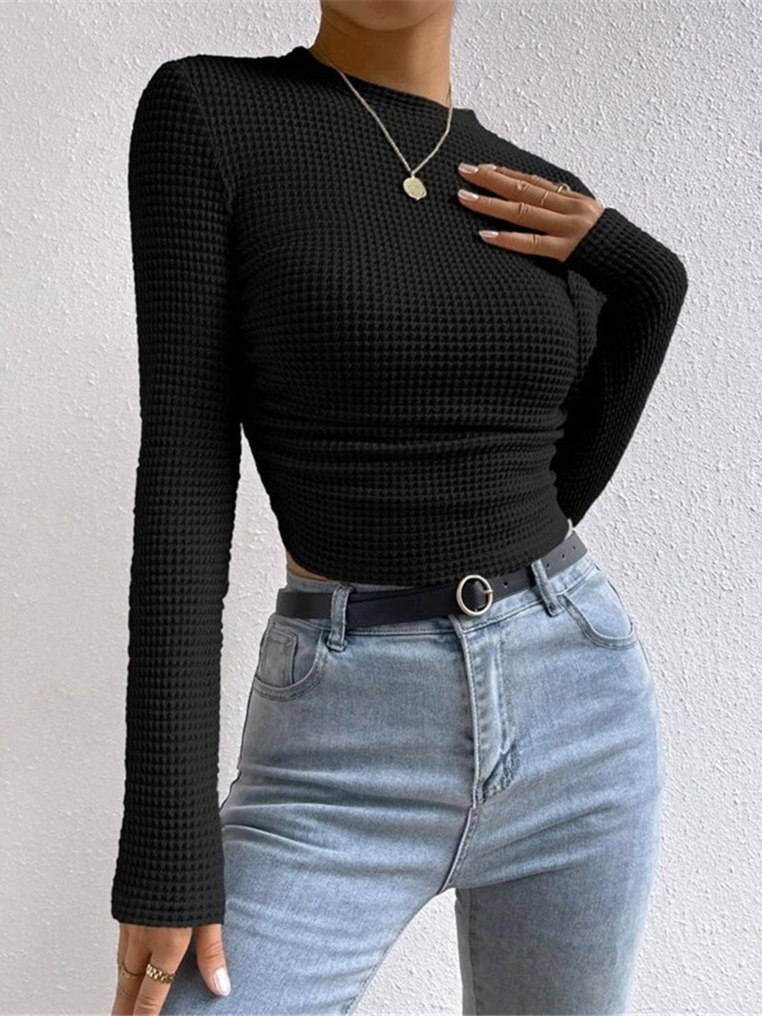 Close-up of the textured knit fabric on a women's long sleeve crop top, round neck detail.