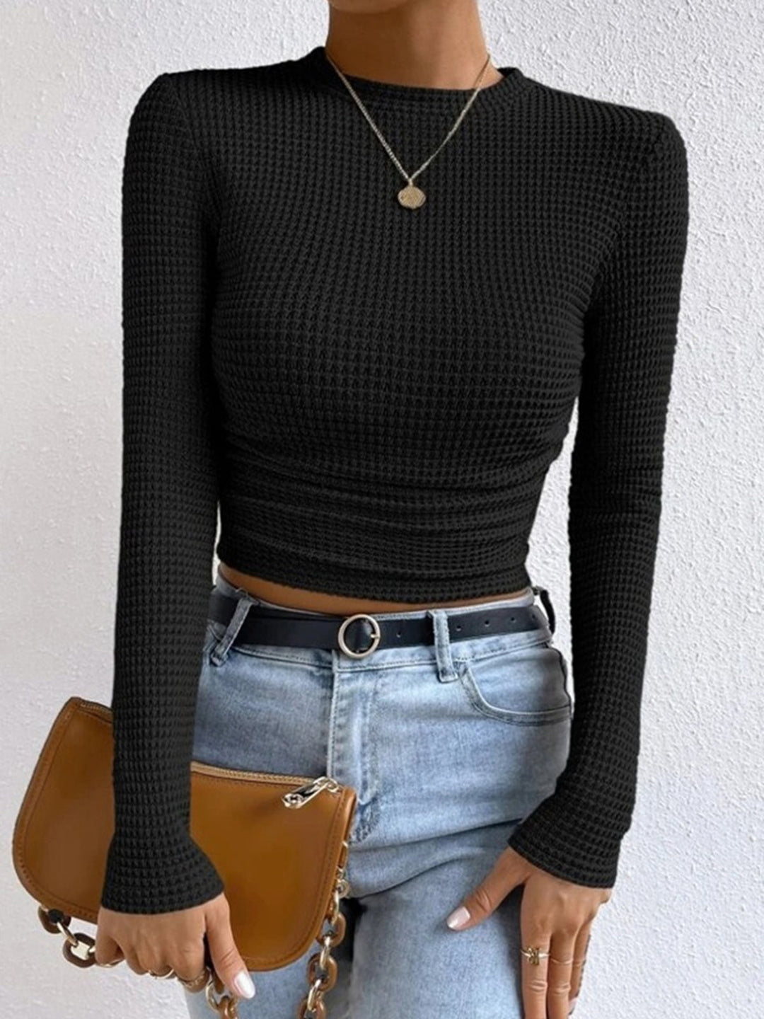 Stylish women's long sleeve crop top paired with high-waisted jeans, casual look.