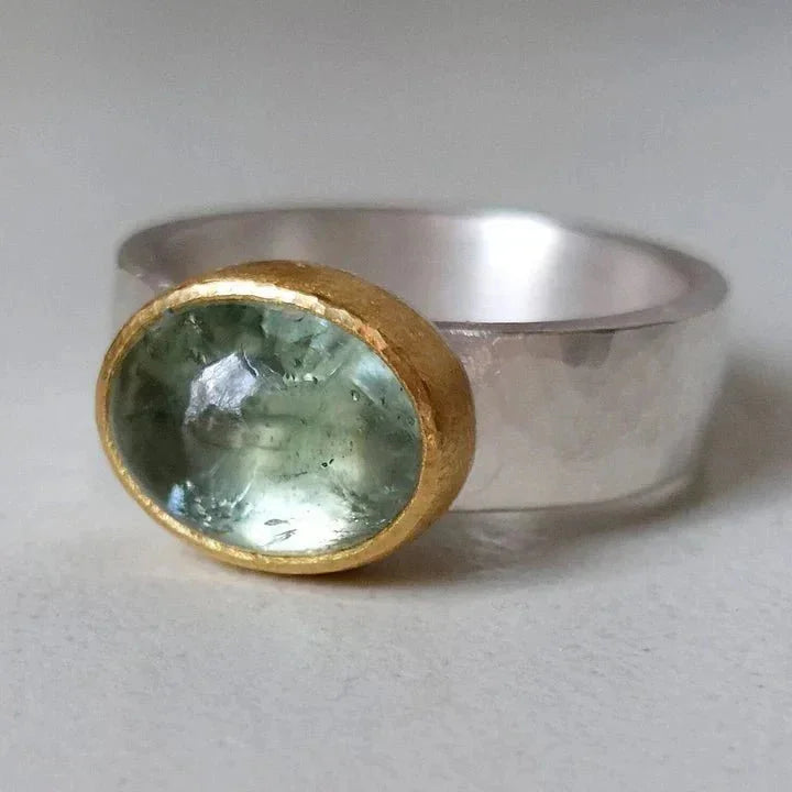 Women's vintage hammered silver-tone ring with an oval green stone in a gold bezel, a stylish fashion accessory.