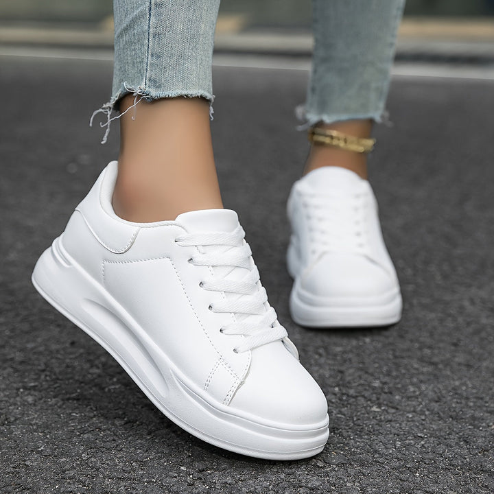 Front view of women's white leather everyday shoes, emphasizing the classic lace-up detail.