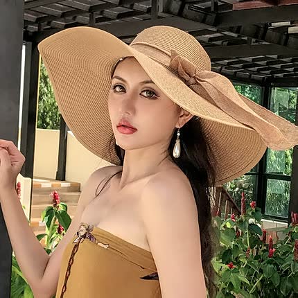Women's wide brim straw sun hat with elegant black bow, perfect for beach or summer vacation.