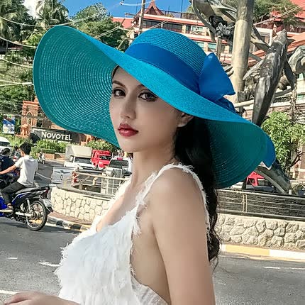 Elegant women's wide brim straw sun hat, adorned with a decorative bow, great for beach, garden, or resort wear.