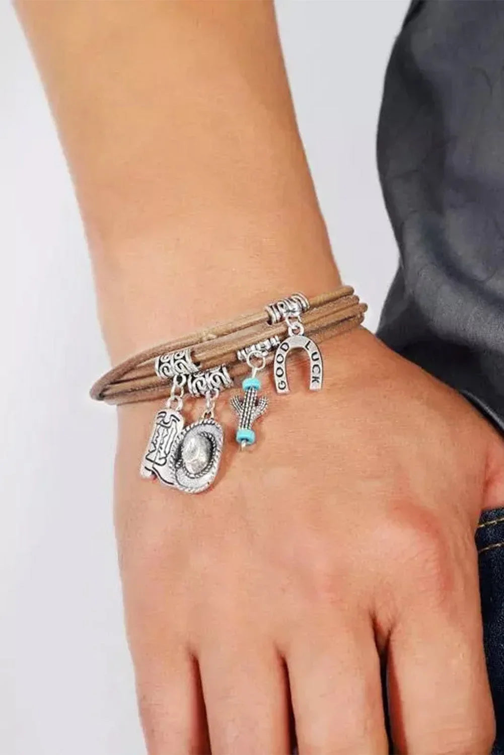 Elegant women's layered western bracelet featuring silver hat and boot charms. Fashionable cowgirl jewelry.